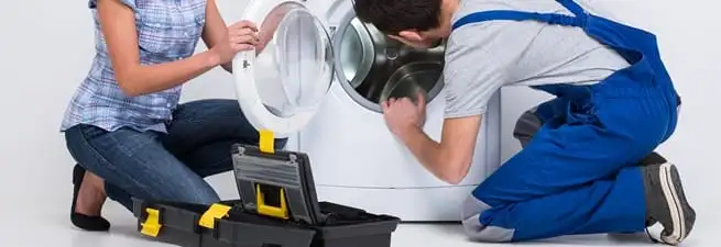 Washer repair technician inspecting a front-load washing machine with tools in Hollywood, FL