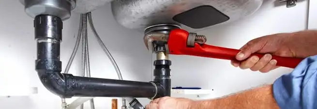 Garbage disposal repair technician tightening the sink drain and disposal connection in Hollywood, FL