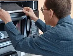 Appliance repair technician replacing a microwave vent filter in Hollywood, FL