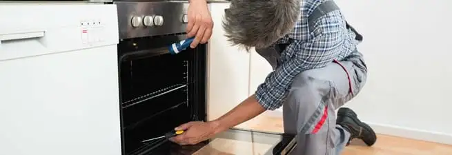 Oven repair technician inspecting and servicing an electric oven in Hollywood, FL