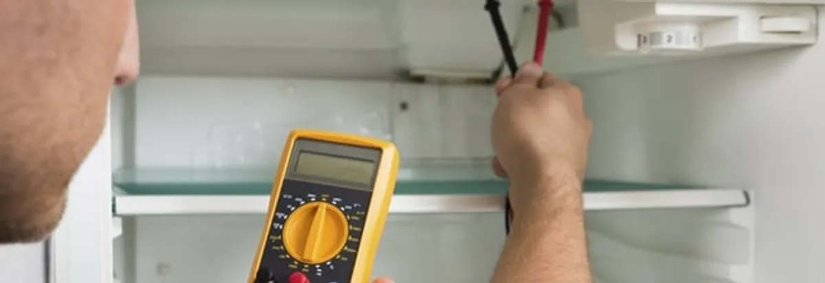 Refrigerator repair technician testing electrical components with a multimeter in Hollywood, FL