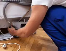 Appliance repair technician fixing refrigerator water line and connections in Hollywood, FL