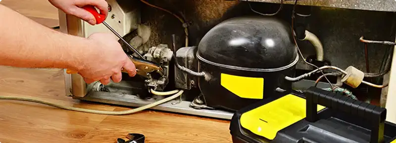 Refrigerator repair technician fixing the compressor and wiring in Hollywood, FL