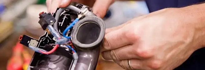 Vacuum repair technician reconnecting wiring and components in Hollywood, FL
