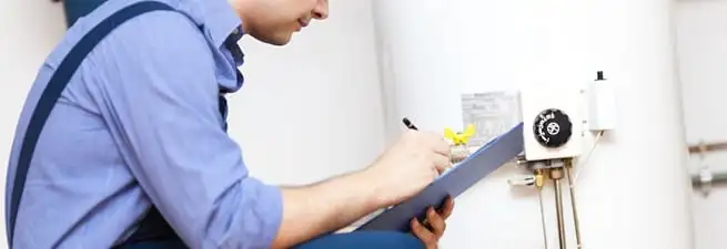 Water heater repair technician inspecting the unit and recording service notes in Hollywood, FL