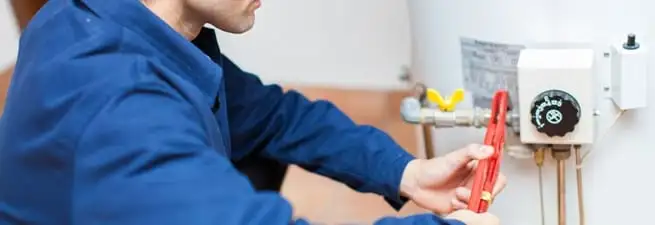 Water heater repair technician adjusting the temperature control and gas valve in Hollywood, FL